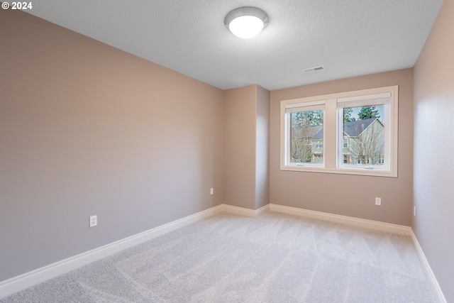 unfurnished room featuring light carpet and a textured ceiling