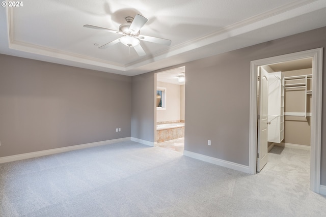 interior space with a spacious closet, ceiling fan, ensuite bathroom, a tray ceiling, and a closet