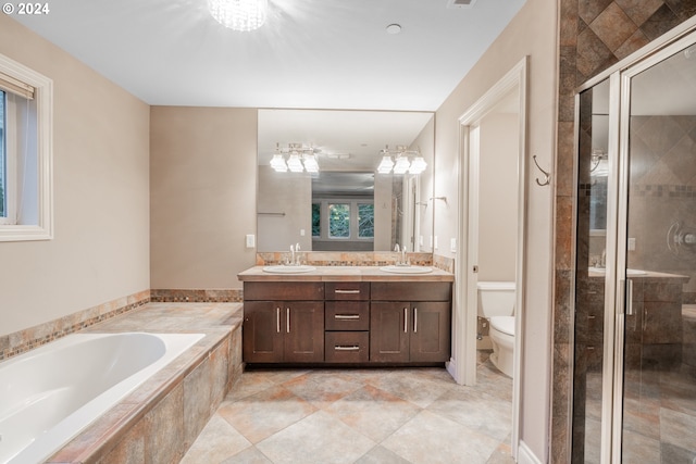 bathroom featuring tiled bath, tile patterned flooring, vanity, and toilet