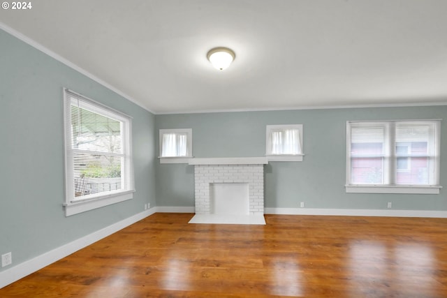 unfurnished living room with hardwood / wood-style floors, a fireplace, and crown molding