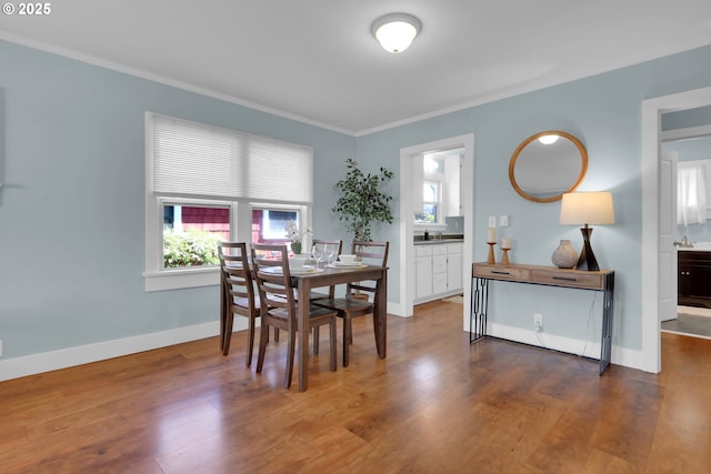 dining area featuring wood finished floors, crown molding, and baseboards
