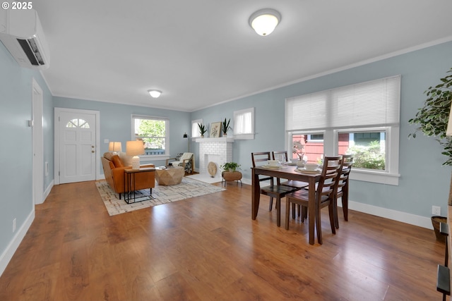 dining room with baseboards, wood finished floors, an AC wall unit, and ornamental molding