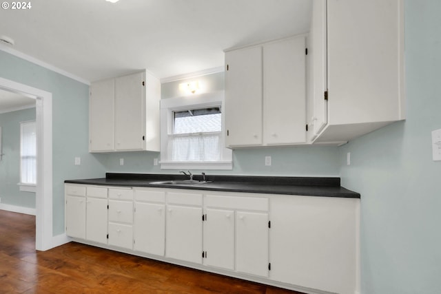 kitchen with white cabinets, dark hardwood / wood-style flooring, ornamental molding, and sink