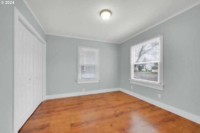 unfurnished bedroom featuring crown molding, a closet, and wood-type flooring