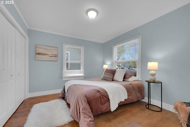 bedroom with baseboards, wood finished floors, and a closet