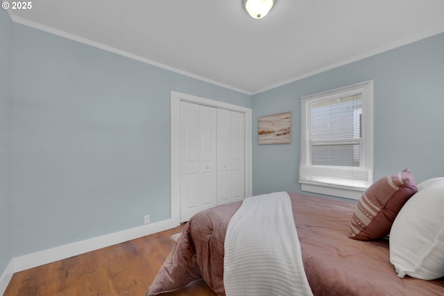 bedroom featuring wood finished floors, a closet, baseboards, and ornamental molding