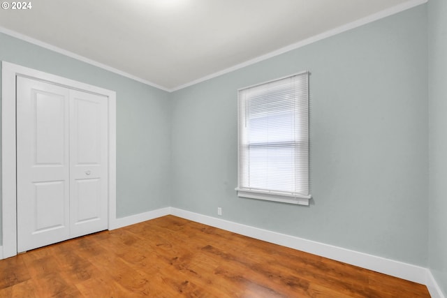 unfurnished bedroom with a closet, wood-type flooring, and ornamental molding