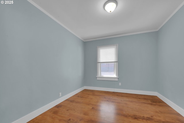 empty room featuring wood finished floors, baseboards, and ornamental molding
