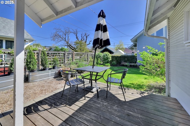 wooden deck featuring a yard, outdoor dining area, and fence