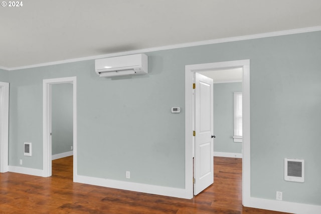 empty room featuring dark hardwood / wood-style flooring, a wall unit AC, and ornamental molding