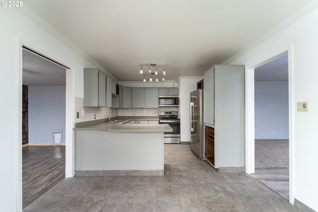 kitchen with kitchen peninsula, appliances with stainless steel finishes, gray cabinetry, crown molding, and sink