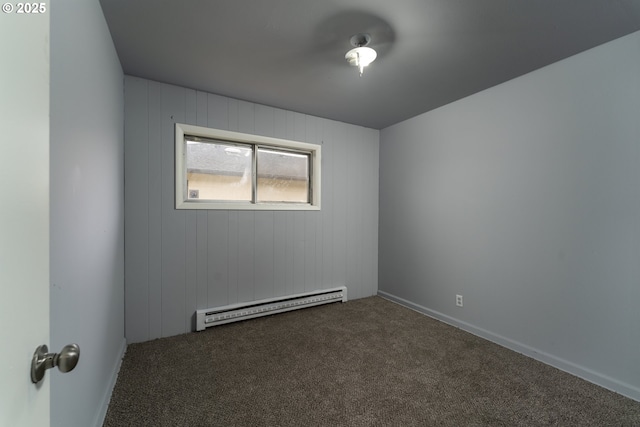 spare room featuring a baseboard radiator and dark carpet