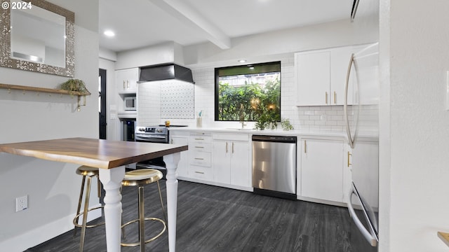 kitchen with beam ceiling, dark wood-style flooring, decorative backsplash, appliances with stainless steel finishes, and white cabinetry