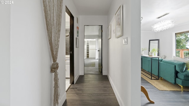 hallway featuring ornamental molding, dark wood-style flooring, visible vents, and baseboards