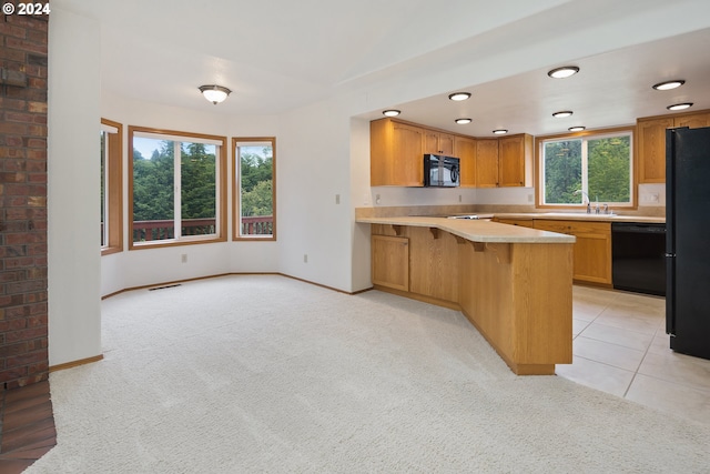 kitchen with kitchen peninsula, black appliances, a kitchen breakfast bar, sink, and light colored carpet