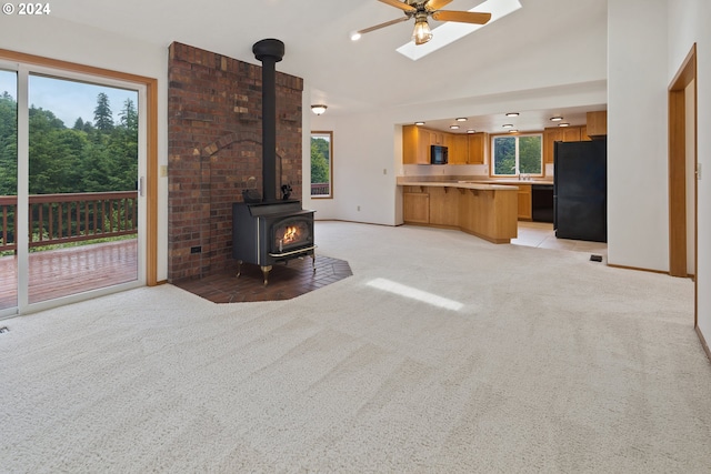 unfurnished living room featuring ceiling fan, a wood stove, and light tile floors