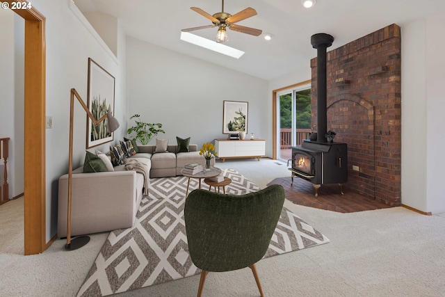 living room featuring dark colored carpet, ceiling fan, vaulted ceiling with skylight, and a wood stove