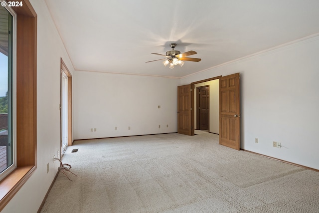 spare room with ornamental molding, ceiling fan, a healthy amount of sunlight, and light colored carpet