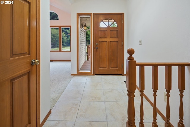 foyer entrance with lofted ceiling and light tile floors