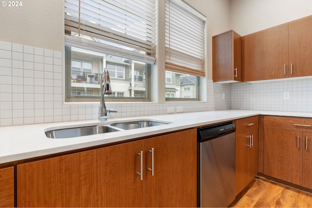 kitchen featuring tasteful backsplash, sink, stainless steel dishwasher, and light hardwood / wood-style floors