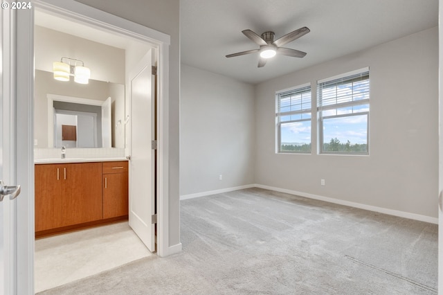 carpeted empty room featuring ceiling fan with notable chandelier and sink