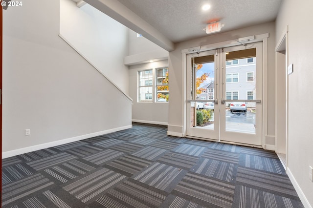 entryway with dark carpet and a textured ceiling