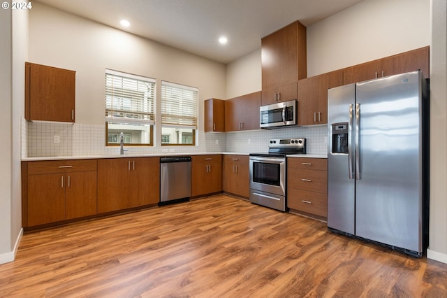 kitchen featuring backsplash, sink, light hardwood / wood-style floors, and appliances with stainless steel finishes