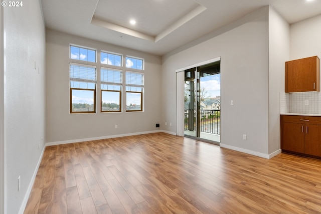 unfurnished room featuring light hardwood / wood-style floors and a tray ceiling