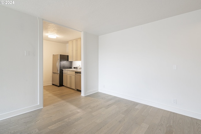 interior space featuring light wood-type flooring, a textured ceiling, stainless steel appliances, sink, and light brown cabinets