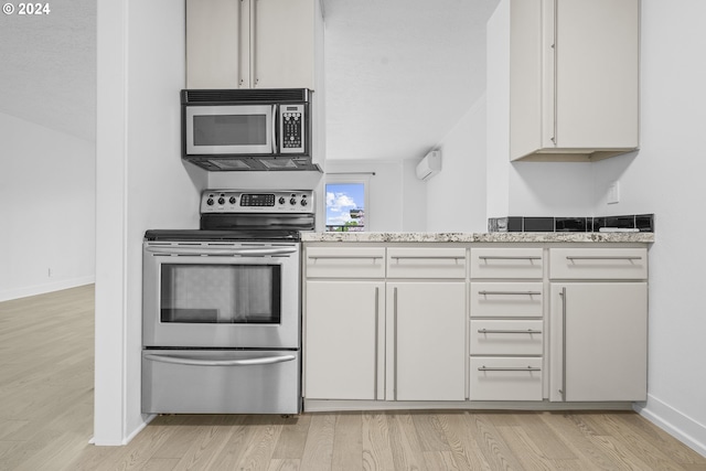 kitchen featuring stainless steel electric range, light stone countertops, white cabinetry, and light hardwood / wood-style flooring