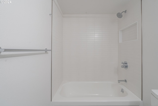 bathroom with tiled shower / bath combo and toilet