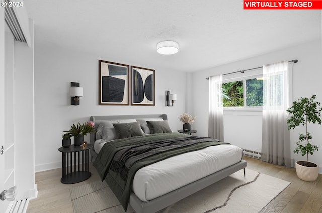 bedroom featuring light wood-type flooring and a baseboard radiator