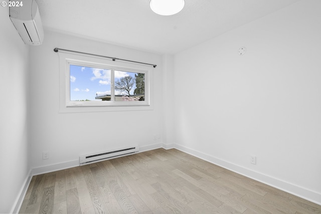 empty room featuring a wall mounted air conditioner, light wood-type flooring, and a baseboard heating unit