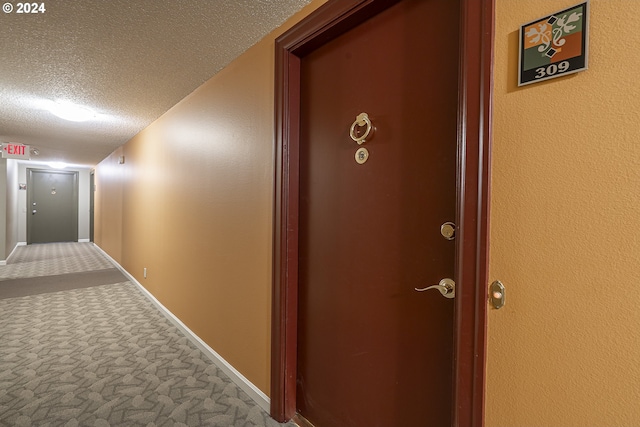 hallway with carpet flooring and a textured ceiling