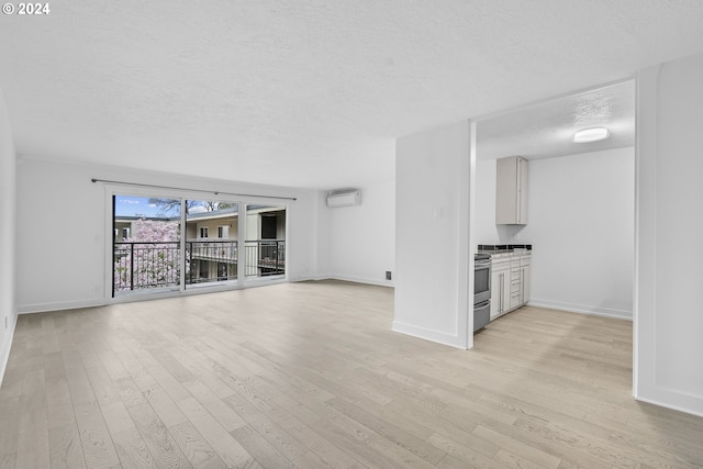 unfurnished living room featuring a textured ceiling, light hardwood / wood-style flooring, and a wall mounted AC