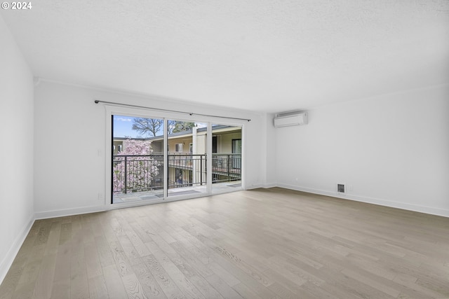 empty room with a wall mounted air conditioner and light hardwood / wood-style flooring