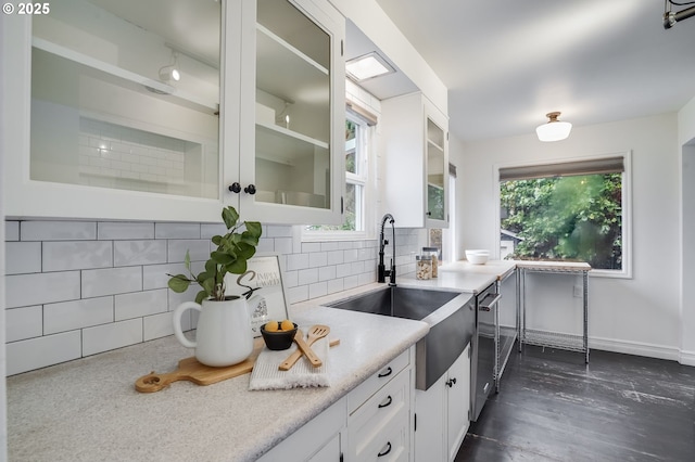 kitchen with white cabinetry, backsplash, sink, and dishwasher