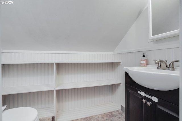 bathroom featuring vanity, toilet, and vaulted ceiling