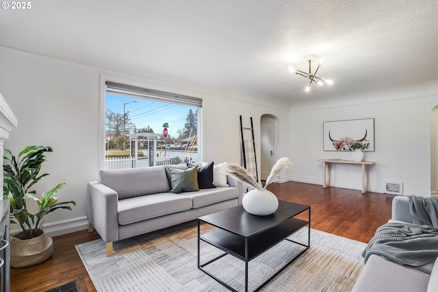 living room featuring hardwood / wood-style floors, a textured ceiling, and an inviting chandelier