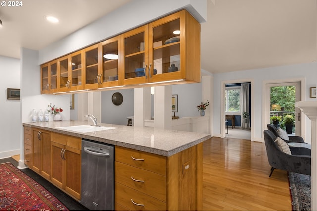 kitchen with dishwasher, glass insert cabinets, light stone counters, a peninsula, and a sink