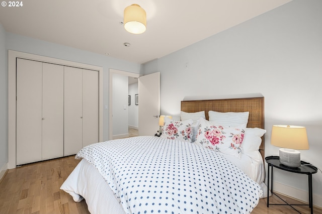 bedroom with a closet, baseboards, and light wood finished floors