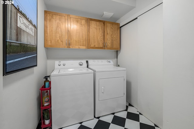 laundry room with washing machine and dryer, cabinet space, visible vents, and light floors