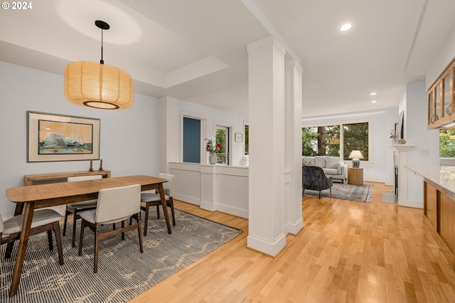 dining space featuring light wood-style floors, recessed lighting, and decorative columns