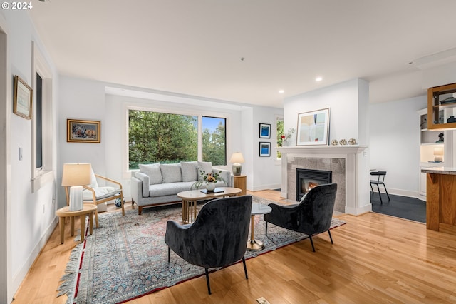 living area featuring baseboards, recessed lighting, a tile fireplace, and light wood-style floors