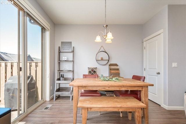 dining room with wood-type flooring and an inviting chandelier