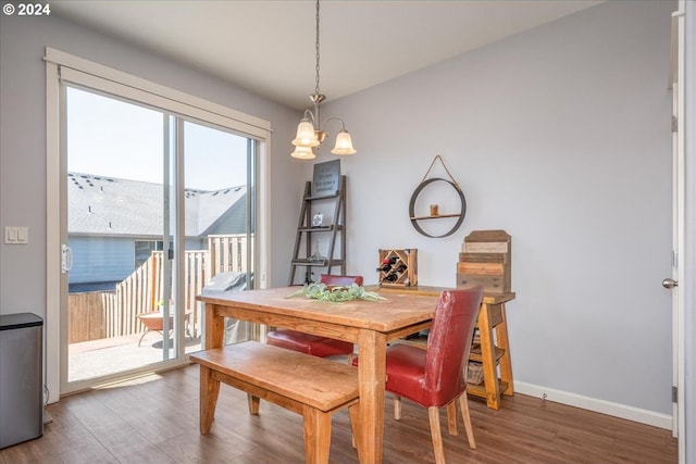 dining space with hardwood / wood-style floors and a notable chandelier