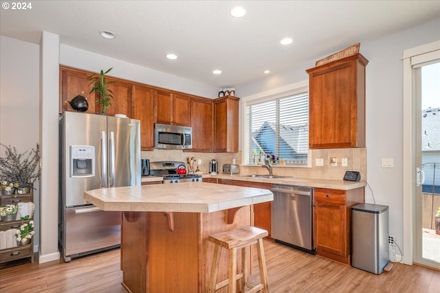 kitchen featuring tasteful backsplash, appliances with stainless steel finishes, a kitchen island, and light hardwood / wood-style floors