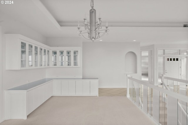 unfurnished dining area with an inviting chandelier and light colored carpet