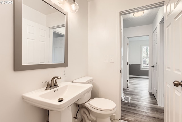 bathroom with a textured ceiling, hardwood / wood-style flooring, and toilet