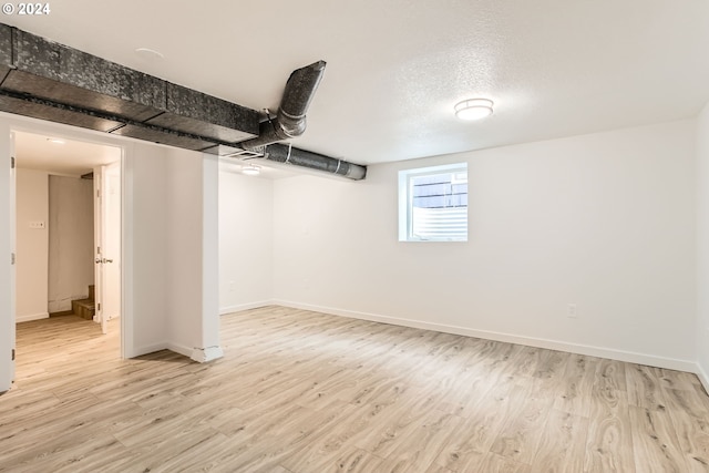 basement featuring light hardwood / wood-style flooring and a textured ceiling